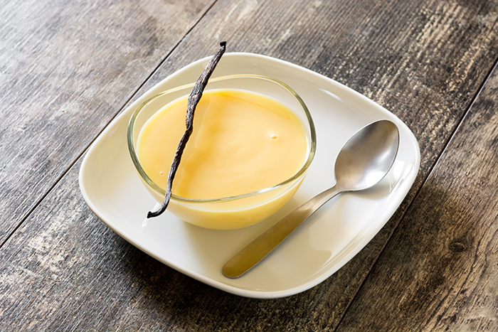 Bowl of homemade vanilla custard on wooden table